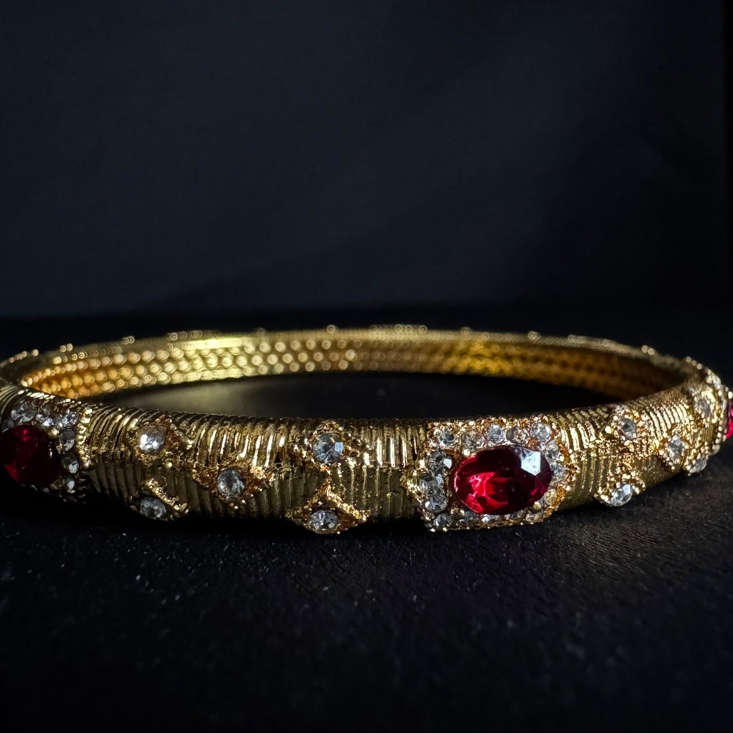 Gold bracelet with red gemstones on a black background